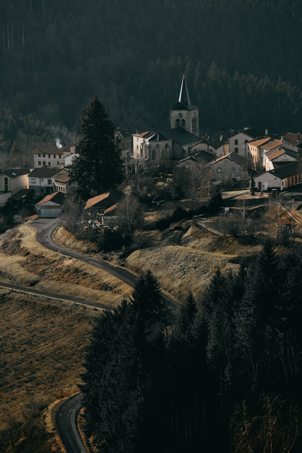 Kľukatá cesta vedie k dedinke na kopci s terakotovou strechou.